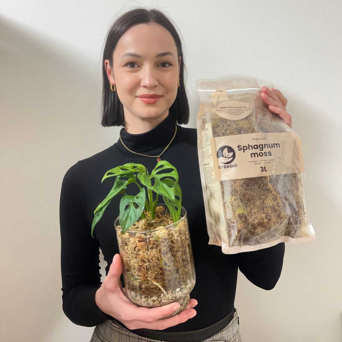 Woman holding potted monstera and sphagnum moss bag