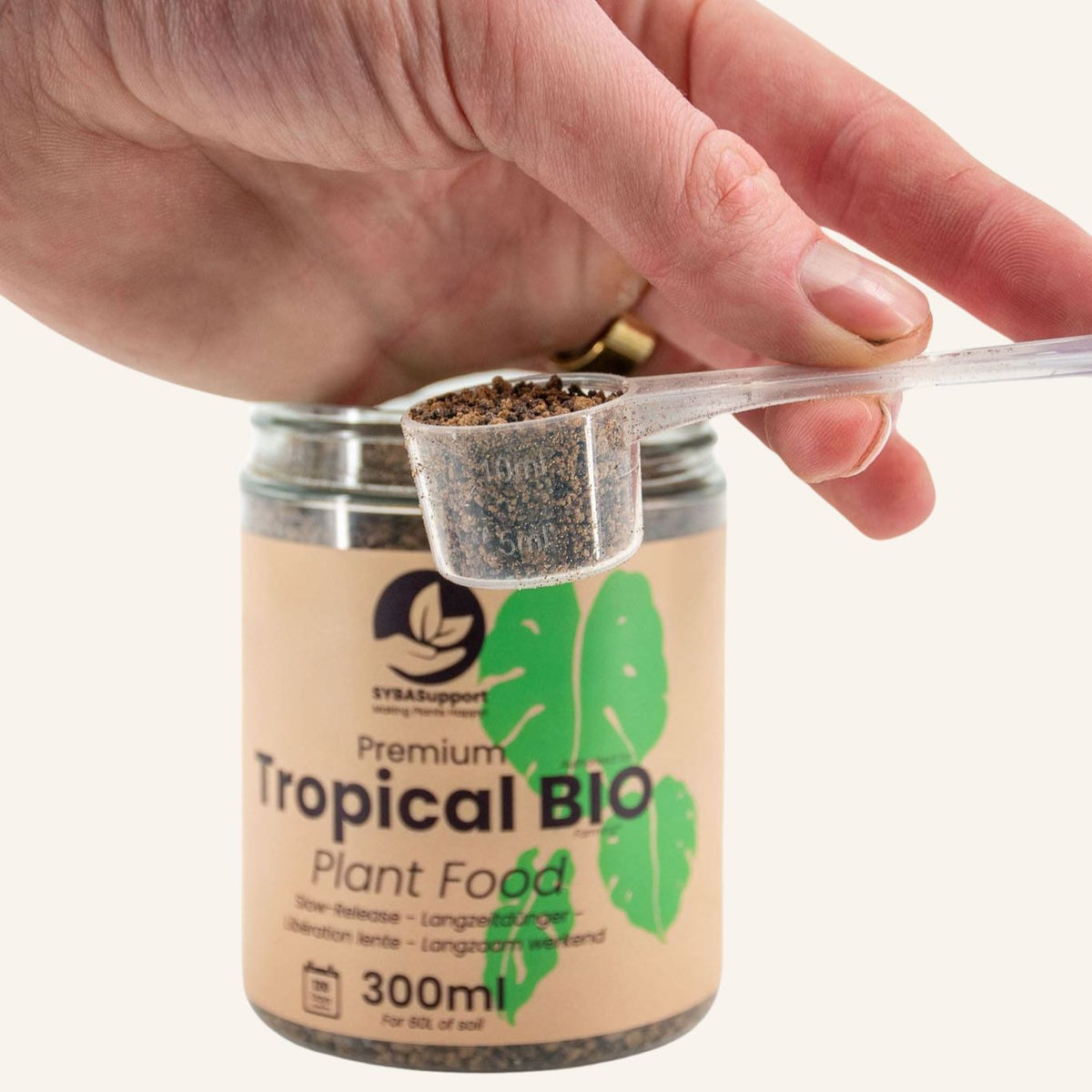 Mão com colher de fertilizante bio de libertação lenta para plantas tropicais sobre frasco
